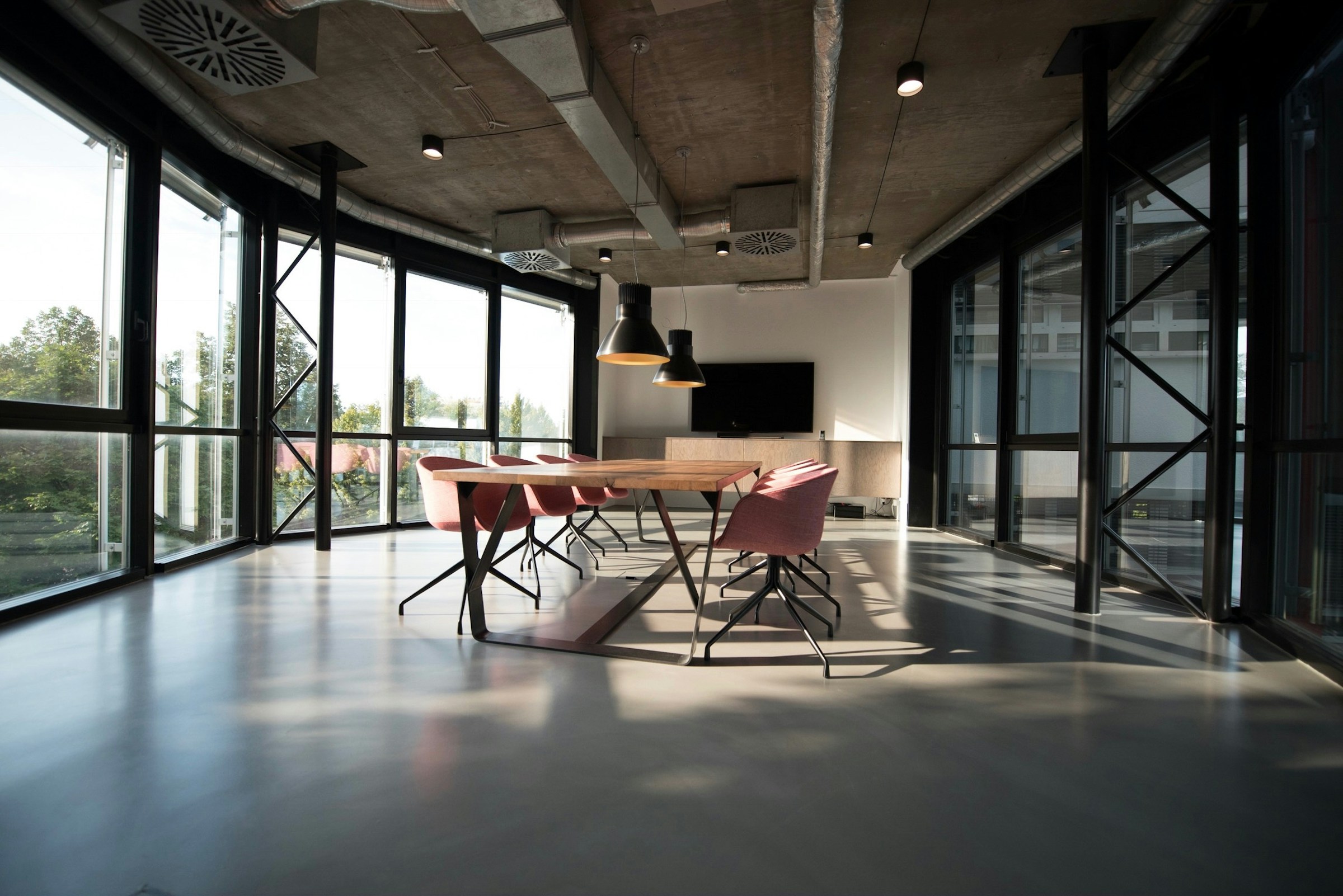 Sunlit meeting room with a long wooden table and tall windows